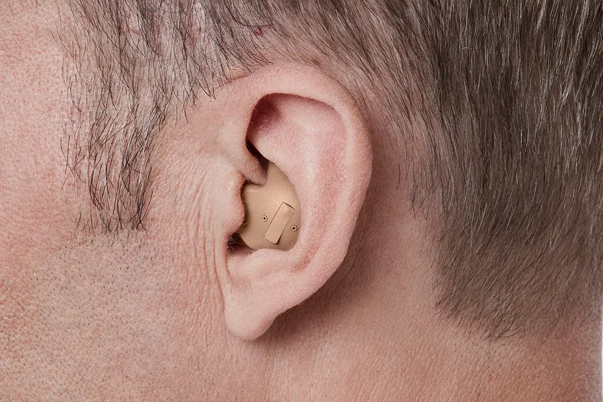 Orelha de um homem usando aparelho feito sob medida na concha da orelha
