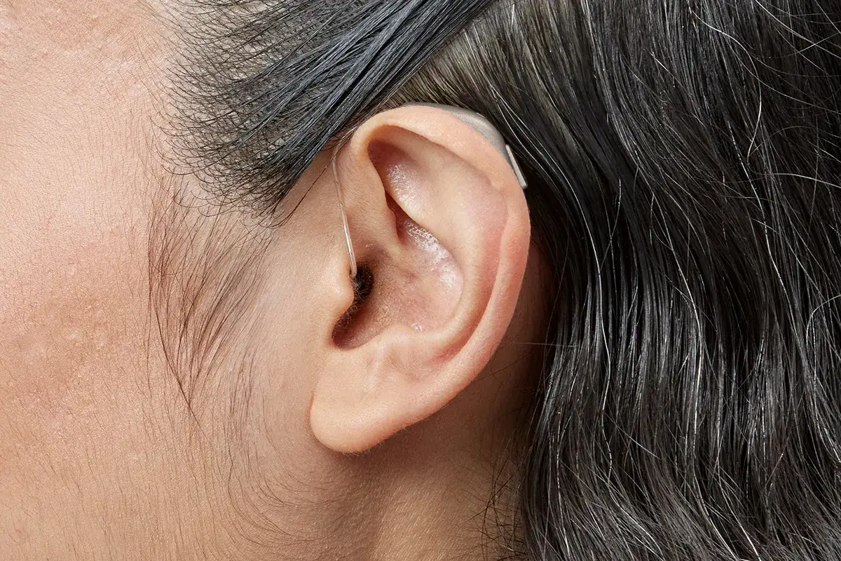 Aparelho auditivo pequeno atrás da orelha, quase escondido pelo cabelo